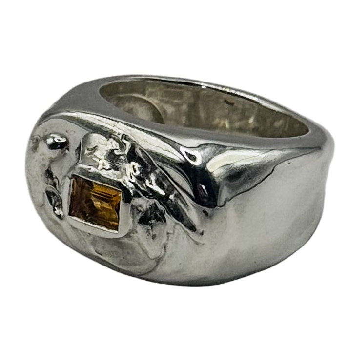 Silver ring with a small orange gemstone on a white background