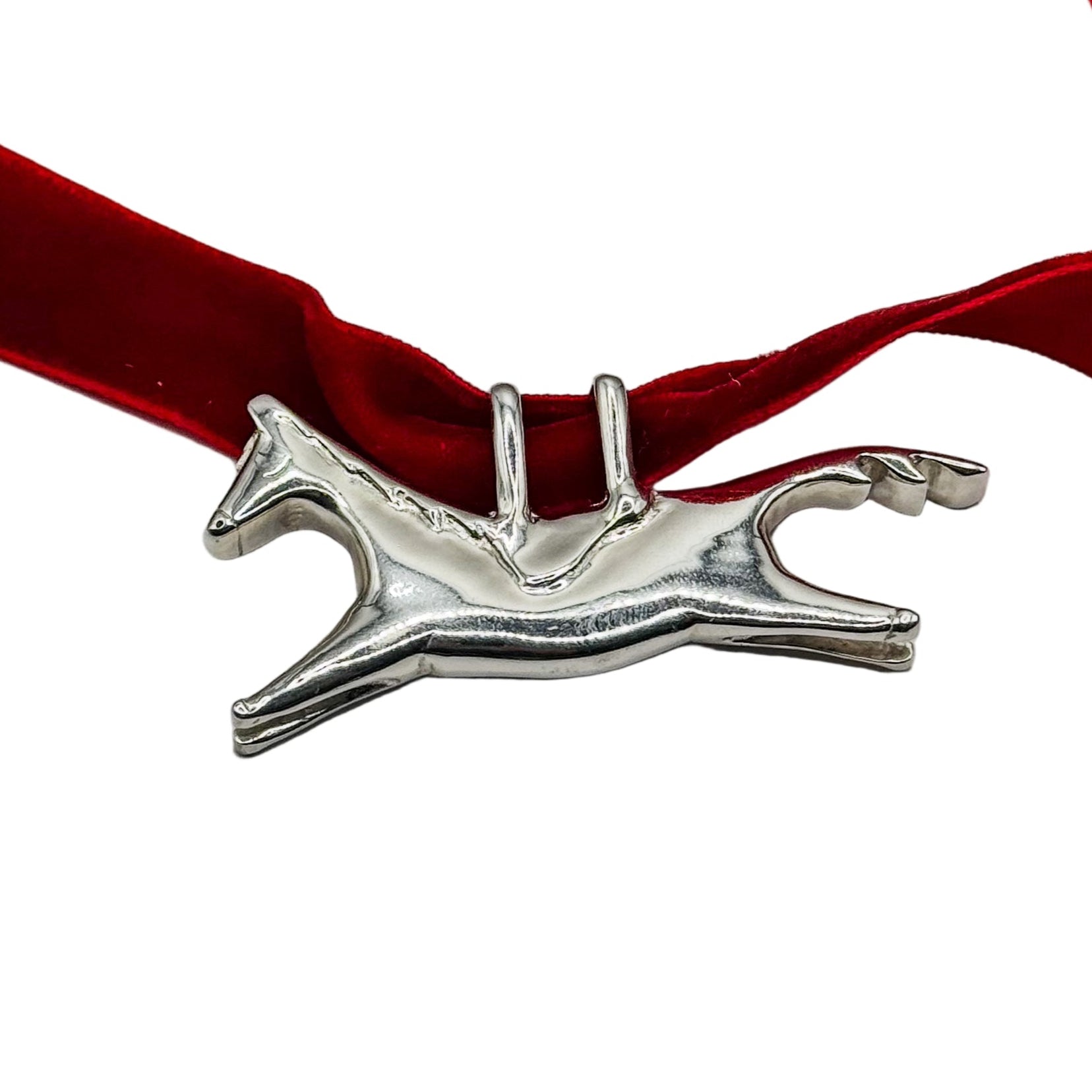 Silver horse-shaped pendant on a red velvet ribbon against a white background